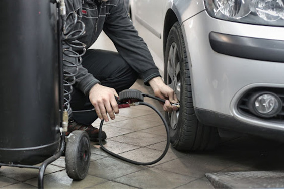A man checking the pressure in a car tire